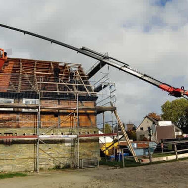 Unser Ladekran mit unserer Schuttmulde unterstützt bei Dachdeckerarbeiten