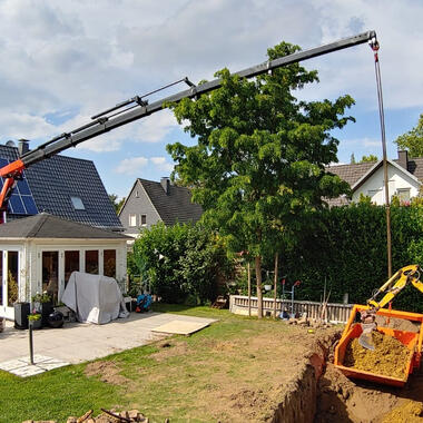 Hand in Hand arbeiten Ladekran und Bagger beim ausheben des Pools