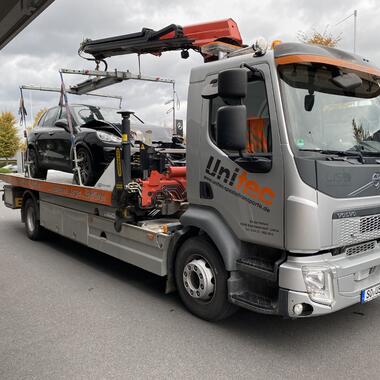 Umsetzen mit Kran eines Unfallfahrzeugs vom Autotransporter auf den Hof der Werkstatt