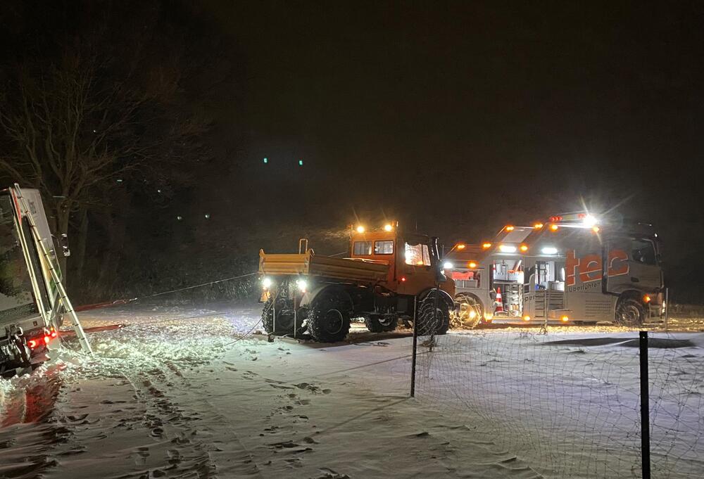 Ein Schneeräumfahrzeug arbeitet bei Nacht in verschneiter Landschaft.