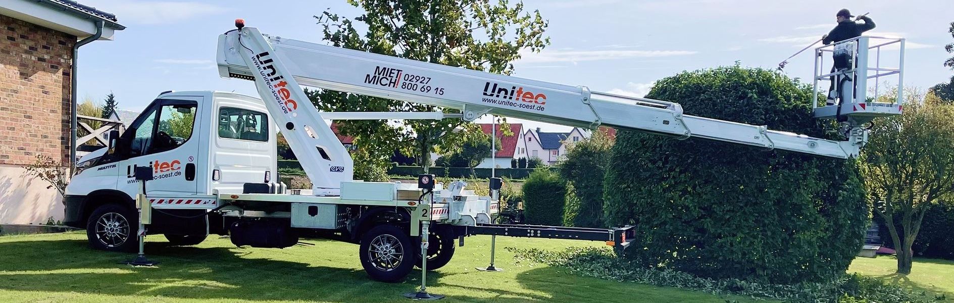 Gartenpflege mit einem Lkw, der eine Arbeitsbühne für Baumschnitt verwendet.